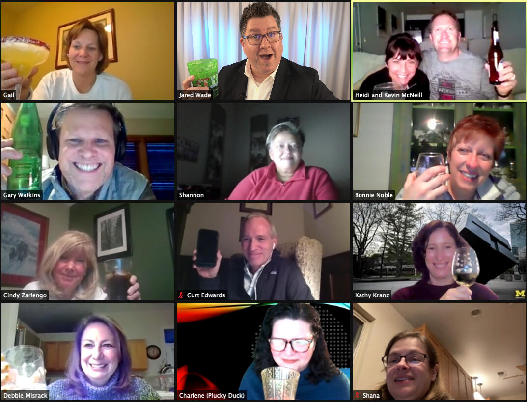 Zoom grid of twelve people raising drinks and smiling from their homes.